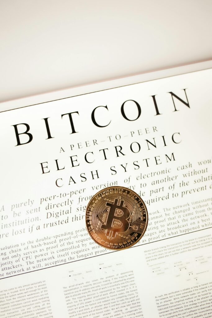 pexels-photo-14348491-14348491 Bitcoin cryptocurrency coin on top of its white paper. Digital currency concept.