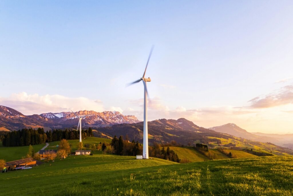 pexels-photo-414807-414807 A wind turbine stands tall against a mountainous backdrop under a vibrant sky at sunset.