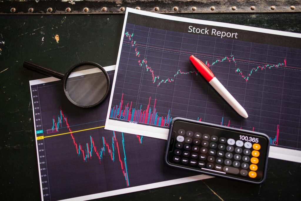 pexels-photo-7947707-7947707 Stock report with charts, calculator, and magnifying glass for financial analysis.