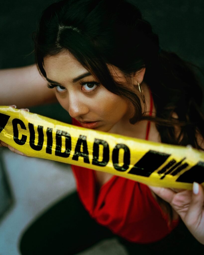 pexels-photo-2701273-2701273 Young woman in red top holding caution tape, conveying intensity and alertness.